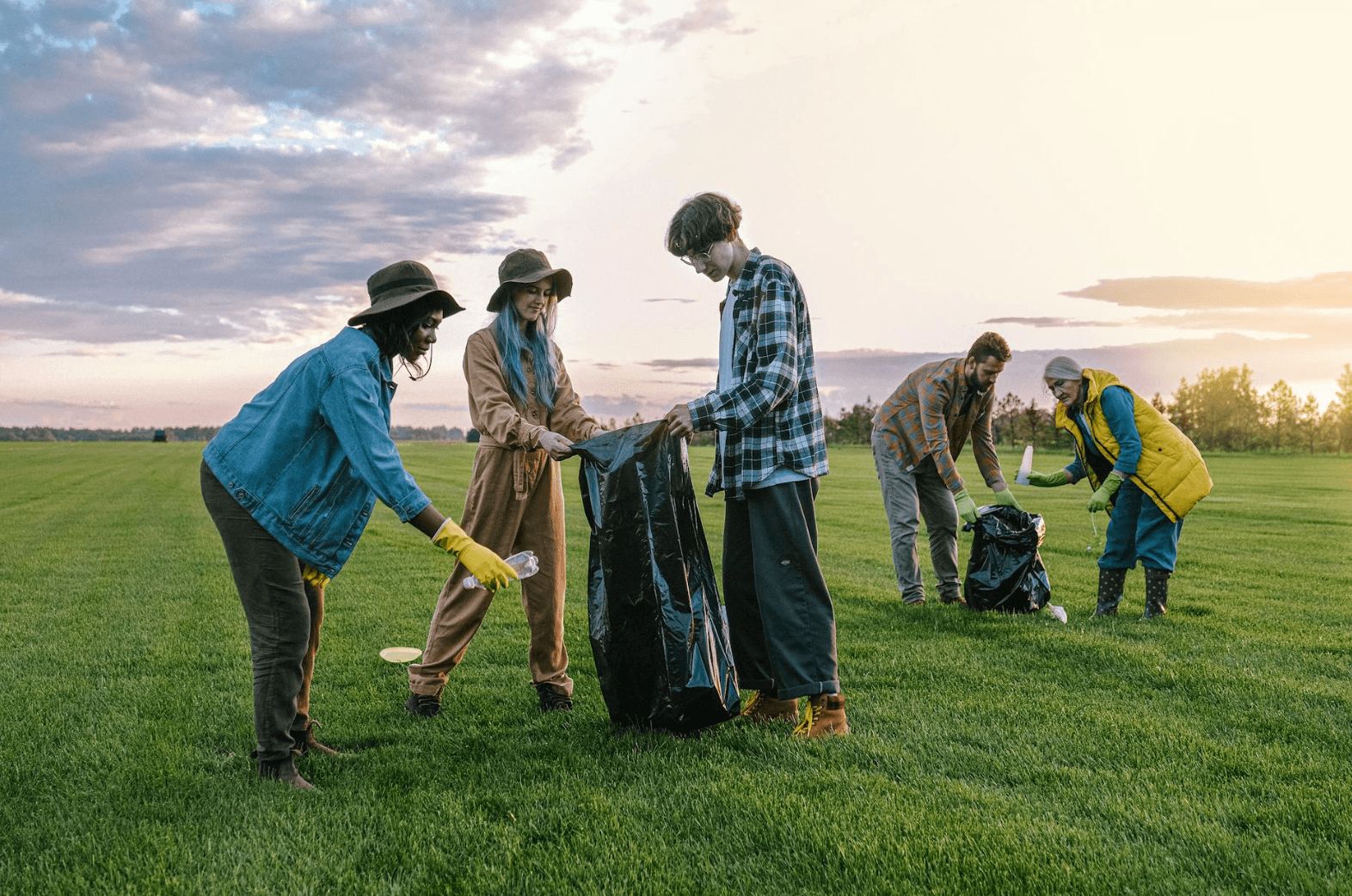 Community members picking up trash in a field.